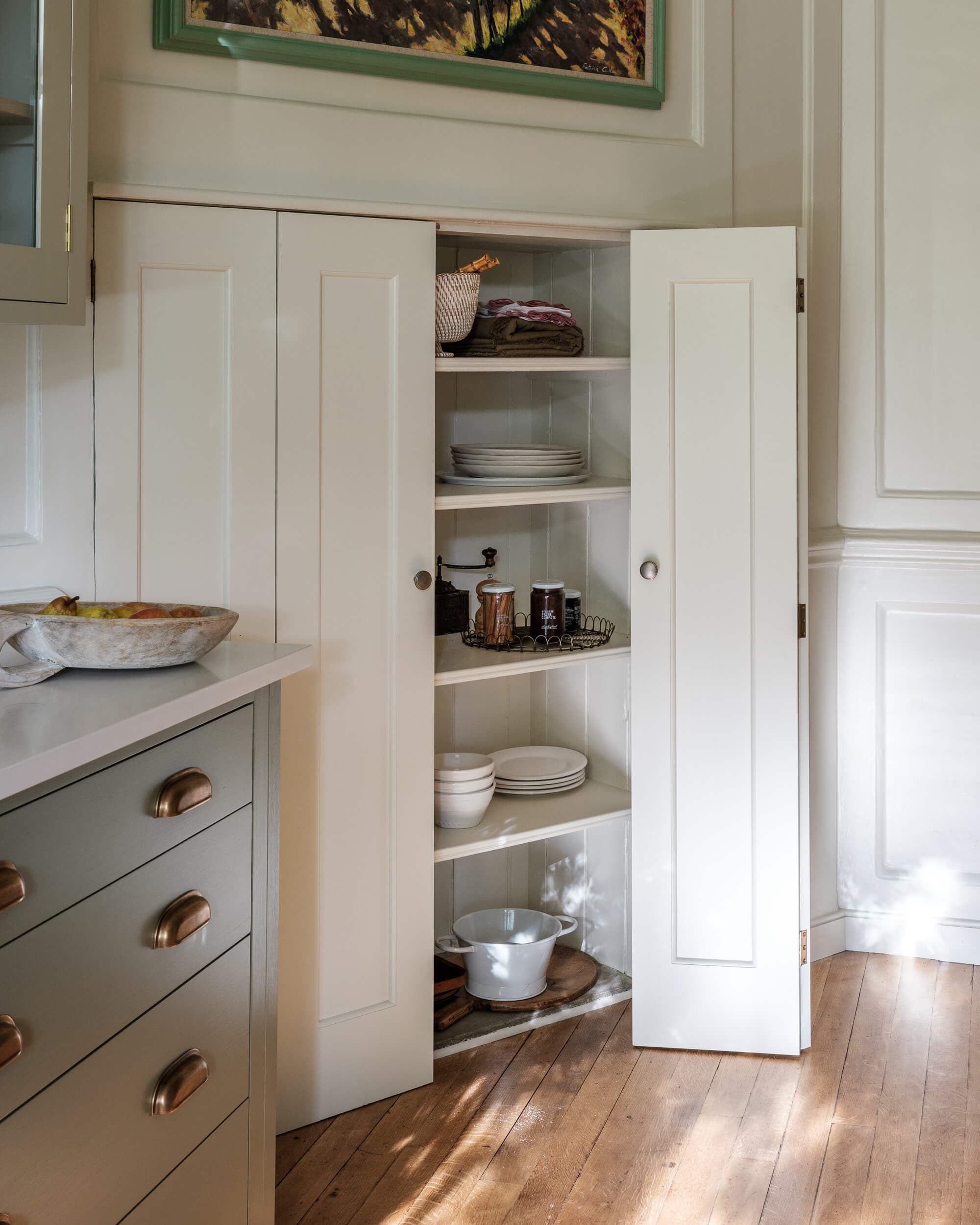 Close view of the kitchen joinery, showing hand-painted cabinet doors and aged brass hardware