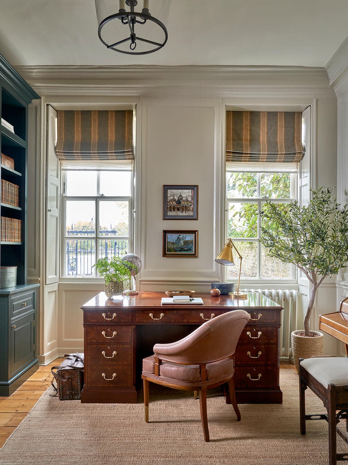 The study's antique desk set against the window, with a leather chair and brass desk lamp