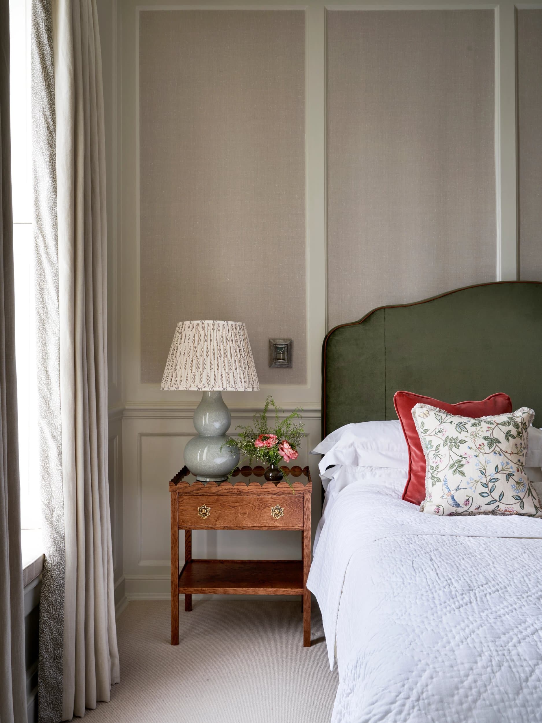 Corner of the principal bedroom, showing panelled walls and an upholstered bench at the foot of the bed