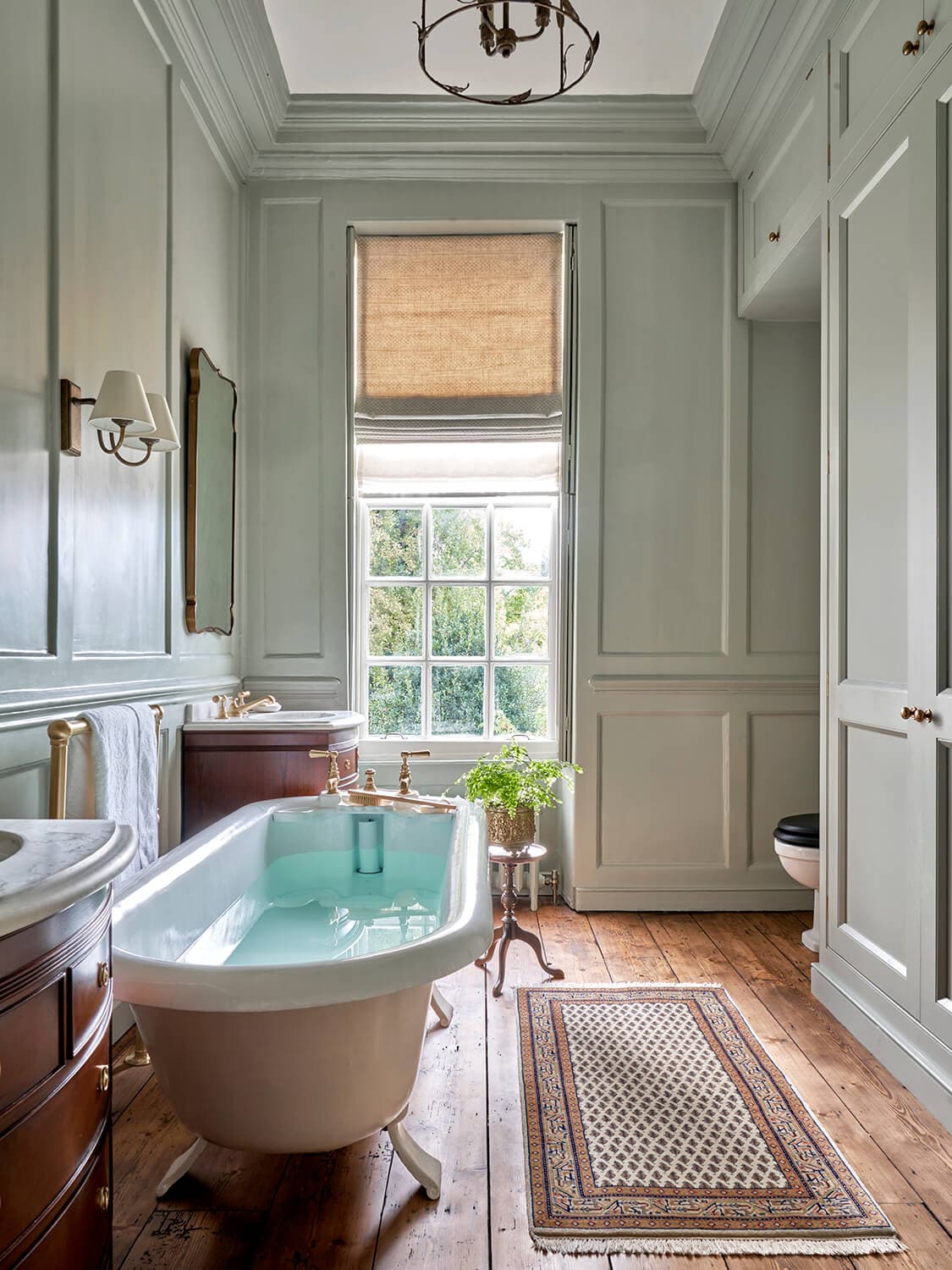 Principal bathroom finished in natural stone, with aged brass fittings and a freestanding bath